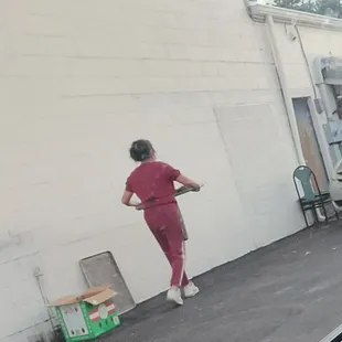 The lady was washing and drying  vegetables of some kind outside on this day and was taking them back inside.
