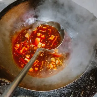 a steaming wok with a spoon in it