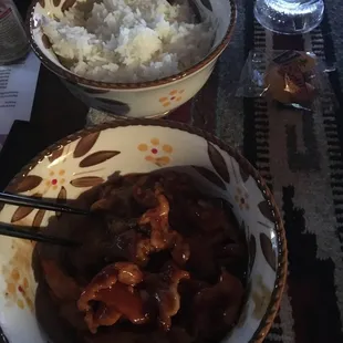 a bowl of rice and a bowl of meat with chopsticks