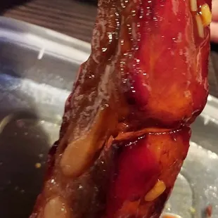 a hand holding a piece of bacon