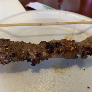 a meat skewer on a paper plate