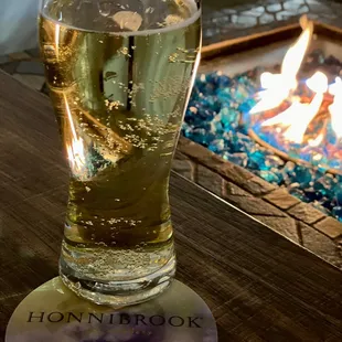 a glass of beer next to a fire pit