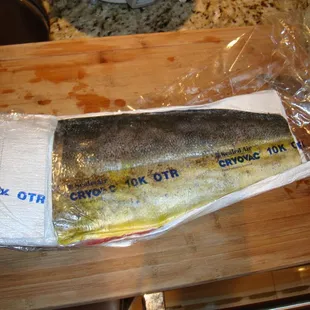 a fish wrapped in plastic on a cutting board