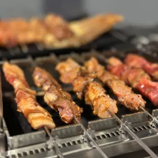 a variety of meats being cooked on a grill