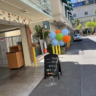 a sign with balloons attached to it