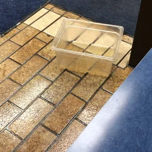 Water sitting all over floor and dripping into bucket from rain dripping from the ceiling.