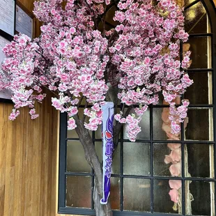 a tree with pink flowers in front of a window