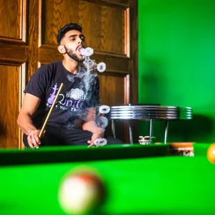 a man smoking on a pool table