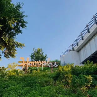 a sign on a hill with a bridge in the background