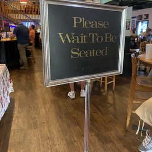 a sign that says please wait to be seated