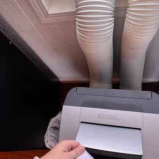 a person holding a piece of paper in front of a printer