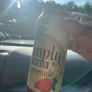 a hand holding a can of simply lemonade