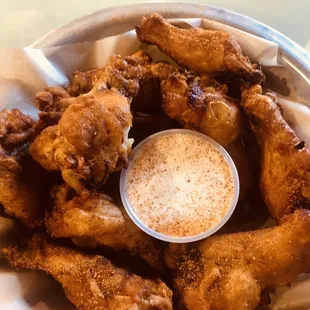 a basket of fried chicken with a dipping sauce