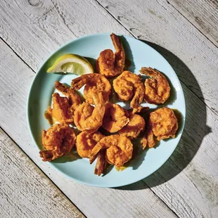a plate of fried shrimp with a lemon wedge