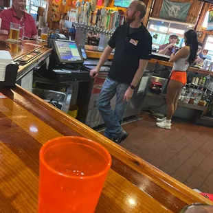 a man standing at a bar with a drink in front of him