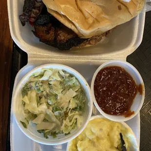 Sliced brisket sandwich on jalapeño bread, barbecue sauce, coleslaw, and potato salad.