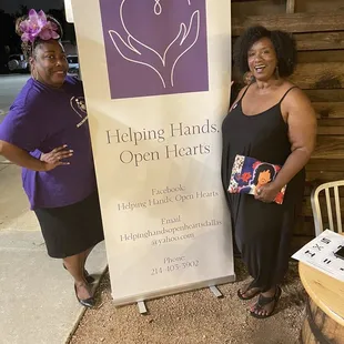 two women standing next to a sign