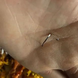 A piece of metal from a cleaning scrub brush found in lo mein