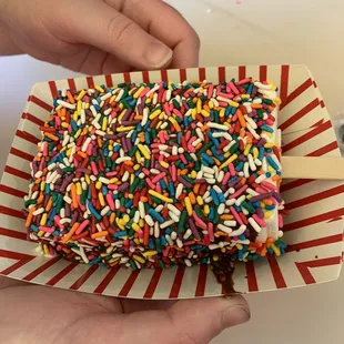 a person holding a box of sprinkles