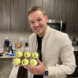a man holding a tray of cupcakes