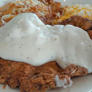 Chicken fried steak with gravy and hash browns.