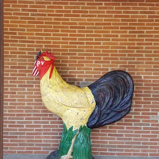a rooster statue in front of a brick wall