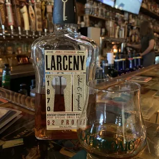 a bottle of larceny bourbon next to a glass of whiskey