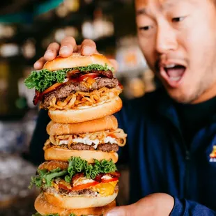 a man holding a stack of hamburgers