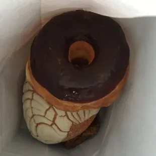 a chocolate frosted donut in a paper bag