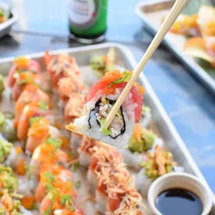 a tray of sushi with chopsticks