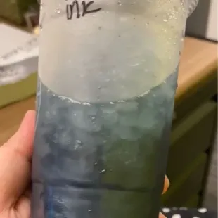 a hand holding a cup of blue and green liquid