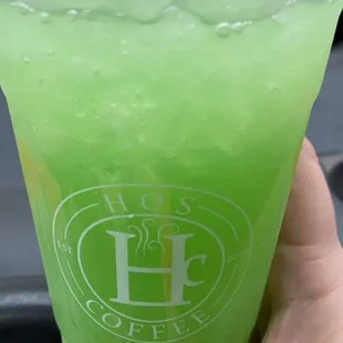 a hand holding a cup of green drink