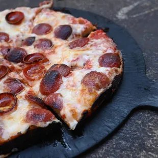 a pepperoni pizza on a pizza stone