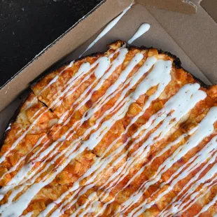 a pizza with white sauce drizzled over it