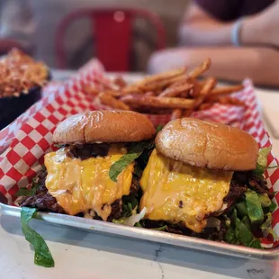 two burgers and fries on a tray