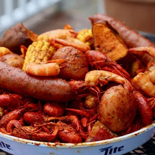 a bowl of crawfish, potatoes, corn, and sausage