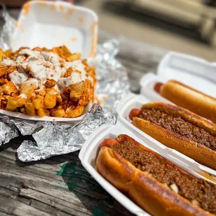 three hotdogs with chili and cheese