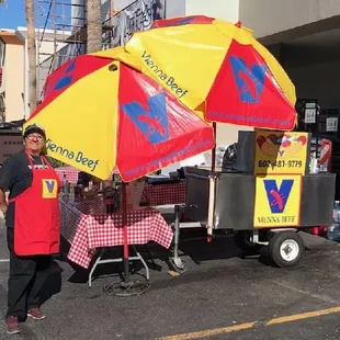a man standing in front of a hot dog cart