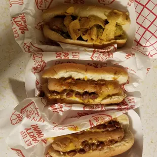 three hotdogs with toppings