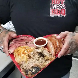 a man holding a heart shaped plate of food