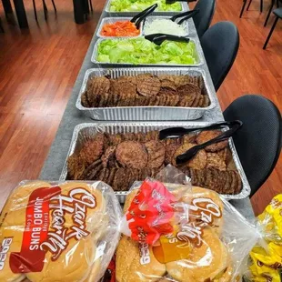 a table of hot dogs, burgers, and other foods