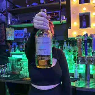 a woman holding a bottle of alcohol