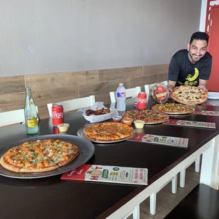 a man sitting at a table with pizzas