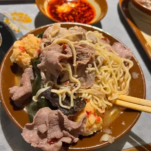 a bowl of noodles with meat and vegetables