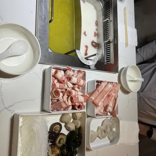 Two bases set in the heated table pot, and fresh ingredients