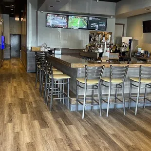 a bar with chairs and televisions