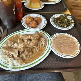Stewed chicken with rice, white beans, collard greens, and hush puppies