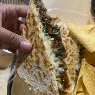 a hand holding a tortilla and chips