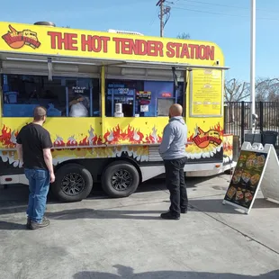 two men standing in front of a food truck