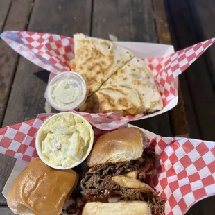 a plate of pulled pork sandwiches with coleslaw and nachos